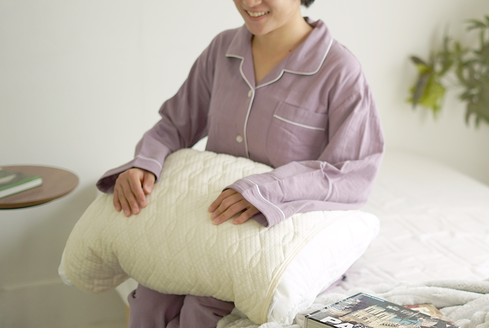 膝に枕をおいて微笑む女性